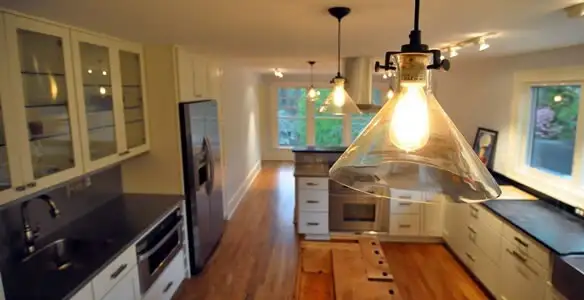 Residential electrician installing modern indoor light fixture in a home in Minneapolis, MN