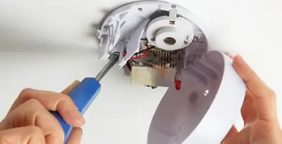 Certified technician wiring smoke detector during installation in Minneapolis, MN